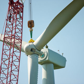 Wind turbine being installed with a red crane against a clear blue sky