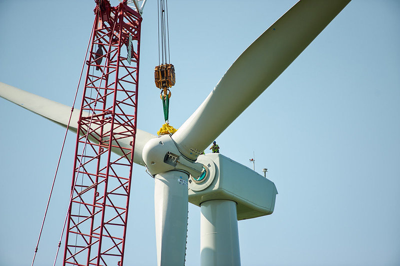 Wind turbine being installed with a red crane against a clear blue sky