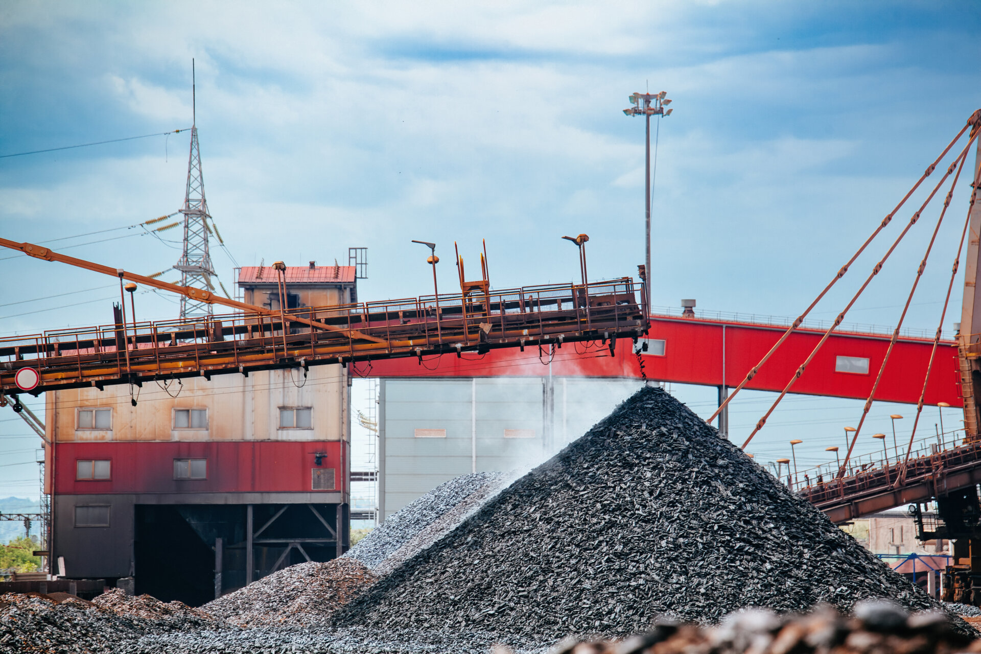 Iron briquette in factory. Excavator digs and loads hot briquetted iron into heap