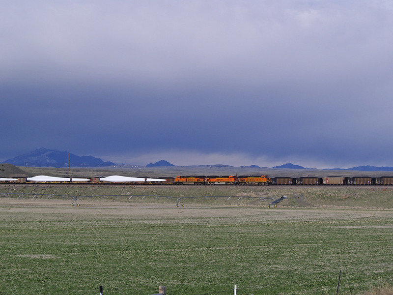 A train carrying wind turbine blades passes a coal train idled on a siding, Orin Junction, Wyoming. Image via Flickr: wildearth_guardian