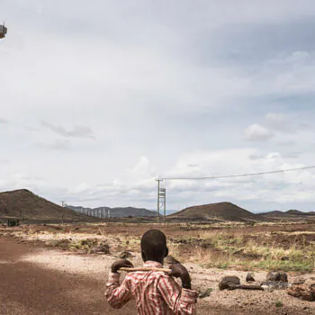 A boy at the Lake Turkana Wind Power installations, rows of turbines, powered by the natural jet stream of air called Turkana Corridorwind, blowing in off the Indian Ocean