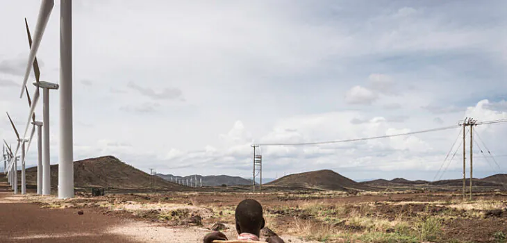 A boy at the Lake Turkana Wind Power installations, rows of turbines, powered by the natural jet stream of air called Turkana Corridorwind, blowing in off the Indian Ocean