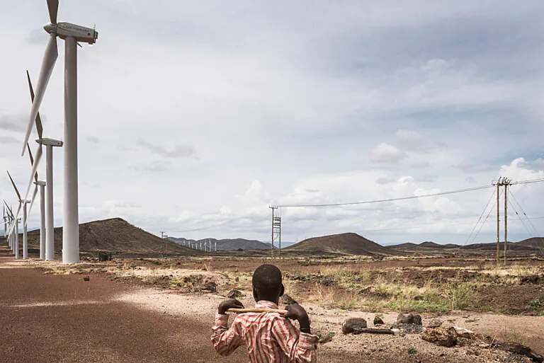 A boy at the Lake Turkana Wind Power installations, rows of turbines, powered by the natural jet stream of air called Turkana Corridorwind, blowing in off the Indian Ocean