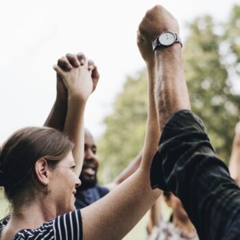 A group of people hold hands in the park