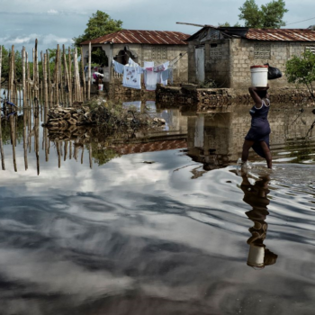 A woman carries supplies through a flooded street in Cap Haitien, Haiti, after extreme flooding. Loss and damage from climate change is hitting communities across the world.