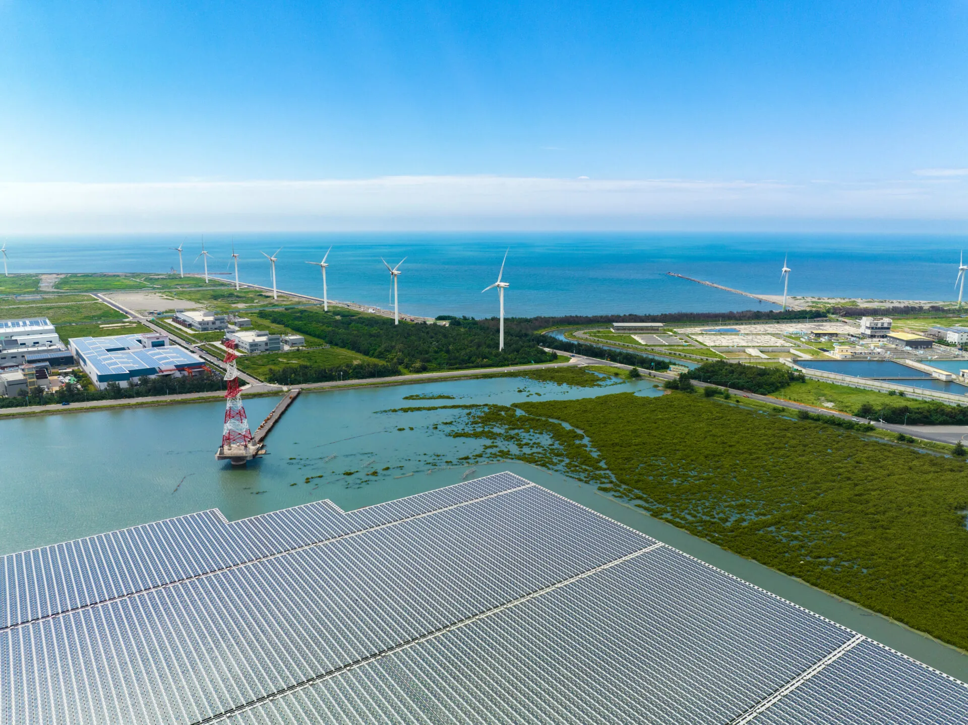 An aerial view shows a solar power plant floating on calm water, with rows of solar panels spread across the surface, capturing sunlight for clean energy.