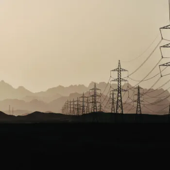 Silhouette of power lines at  dusk in the sandy desert against the background of mountain layers, Egypt.