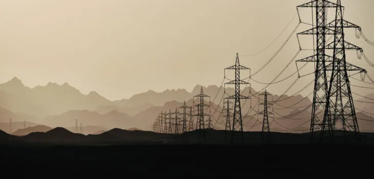Silhouette of power lines at  dusk in the sandy desert against the background of mountain layers, Egypt.