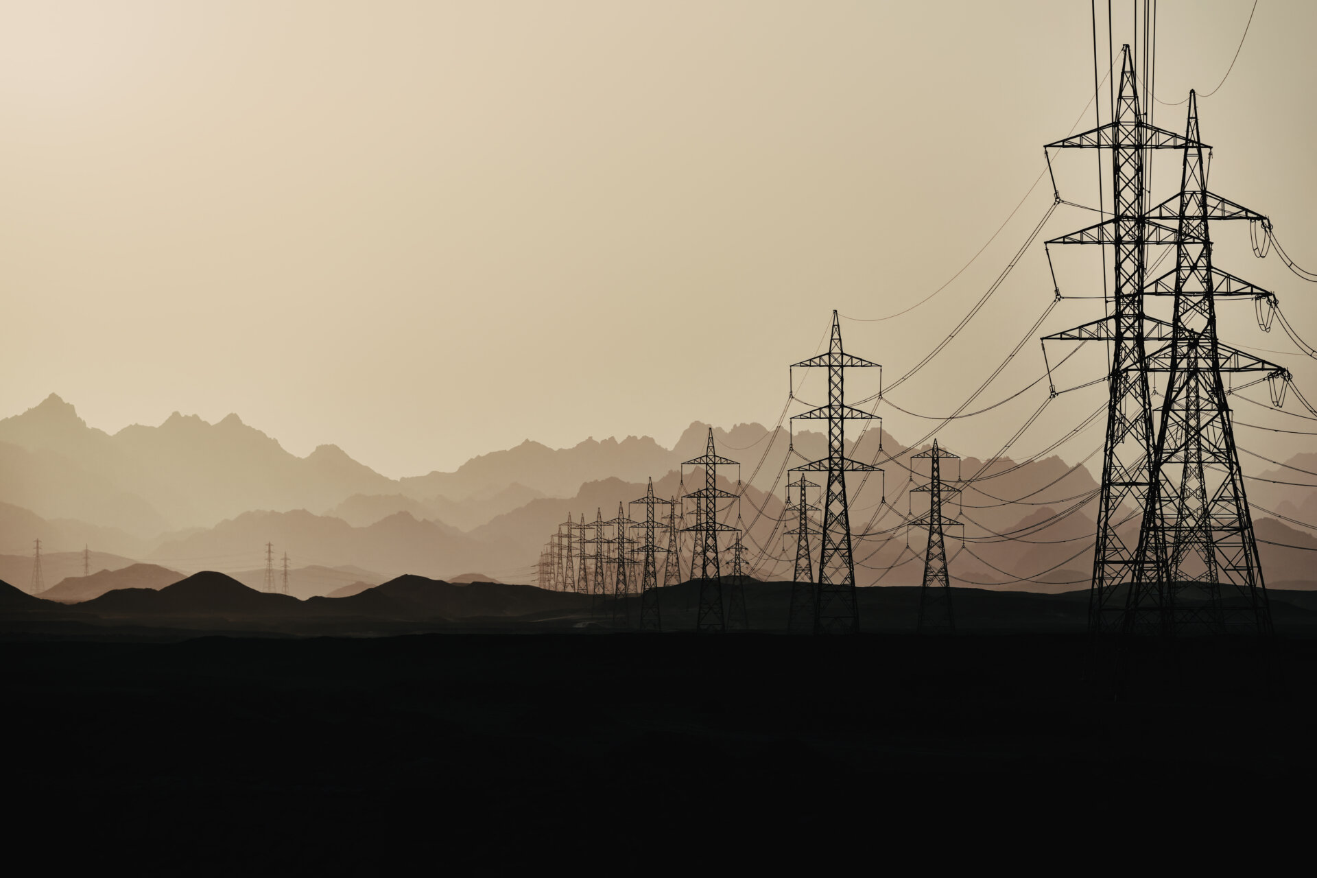 Silhouette of power lines at  dusk in the sandy desert against the background of mountain layers, Egypt.