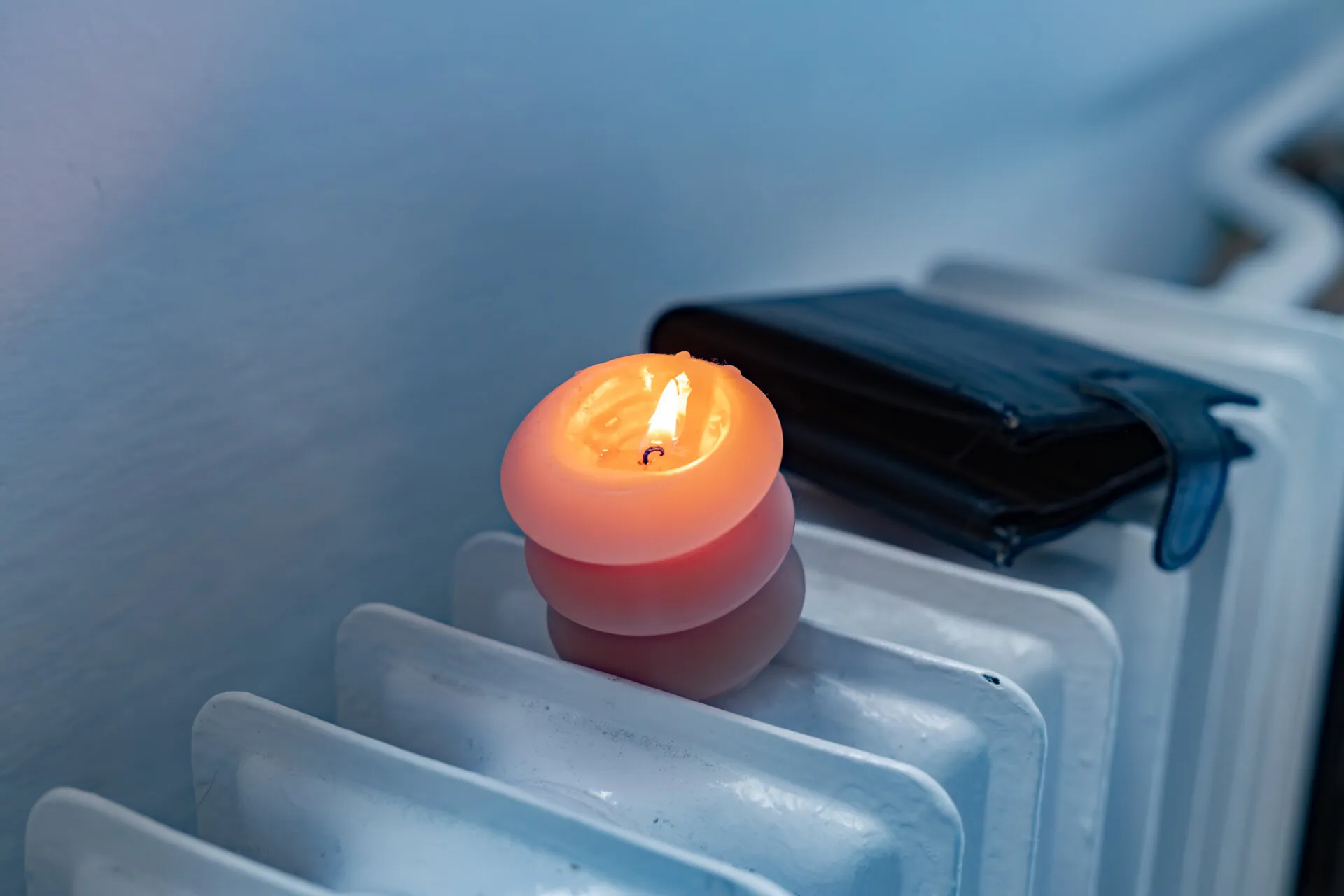 A burning candle, a radiator, and a wallet.