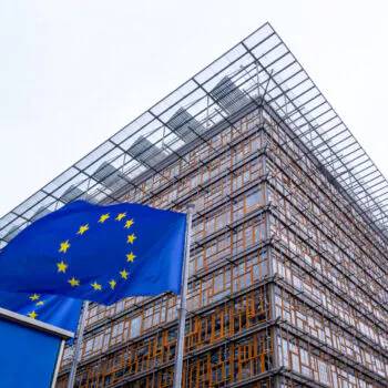 EU flag and the Europa building, headquarter of European Council and Council of the European Union in the European quarter in Brussels, Belgium