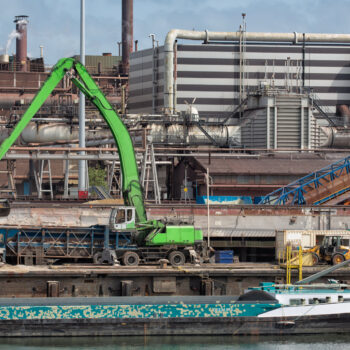 Steel factory in Dutch harbor IJmuiden with crane unloading barge