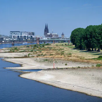 Exposed gravel groynes and dried river bank of the Rhine in Germany due to a severe drought. Cologne Cathedral and Kranhaeuser in background