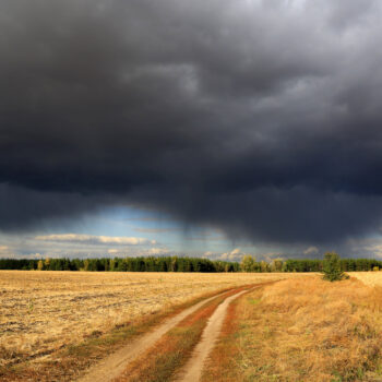Heavy clouds over dirty road in steppe, Autumn day, landscape in Ukraine.