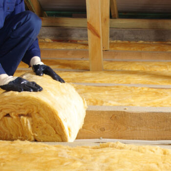 Worker thermally insulating house attic with glass wool