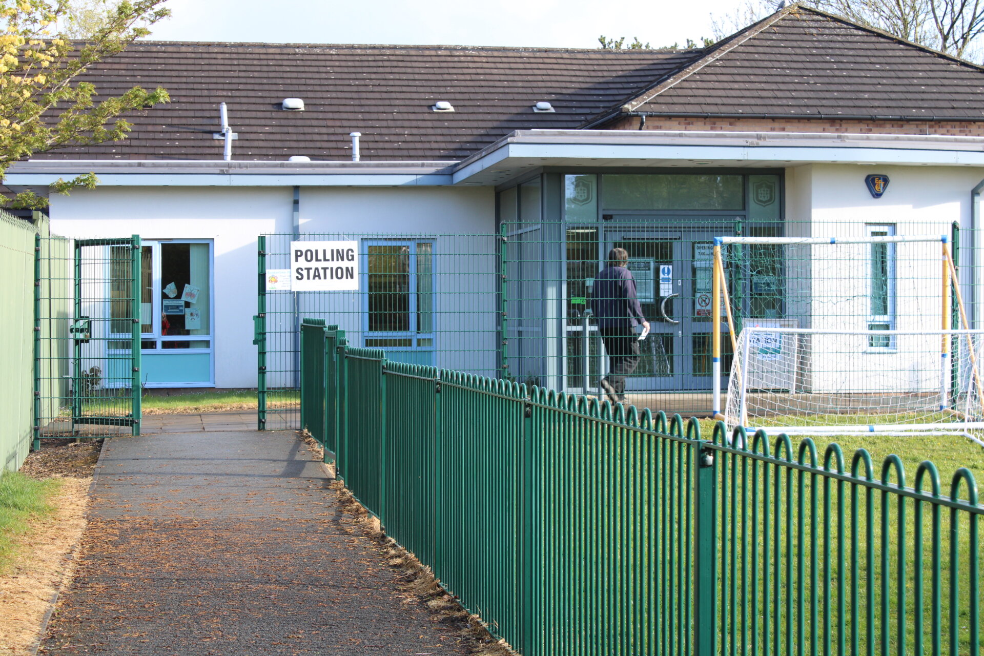 School being used as polling station with rear view of a man about to enter the building