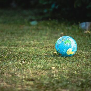 Blue and white desk globe on green grass.