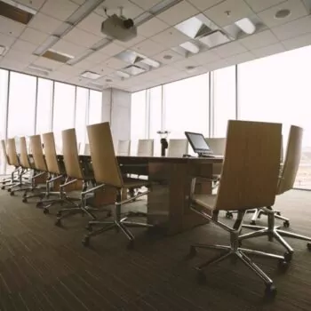 Board of director's oval table in a meeting room with big windows in the background