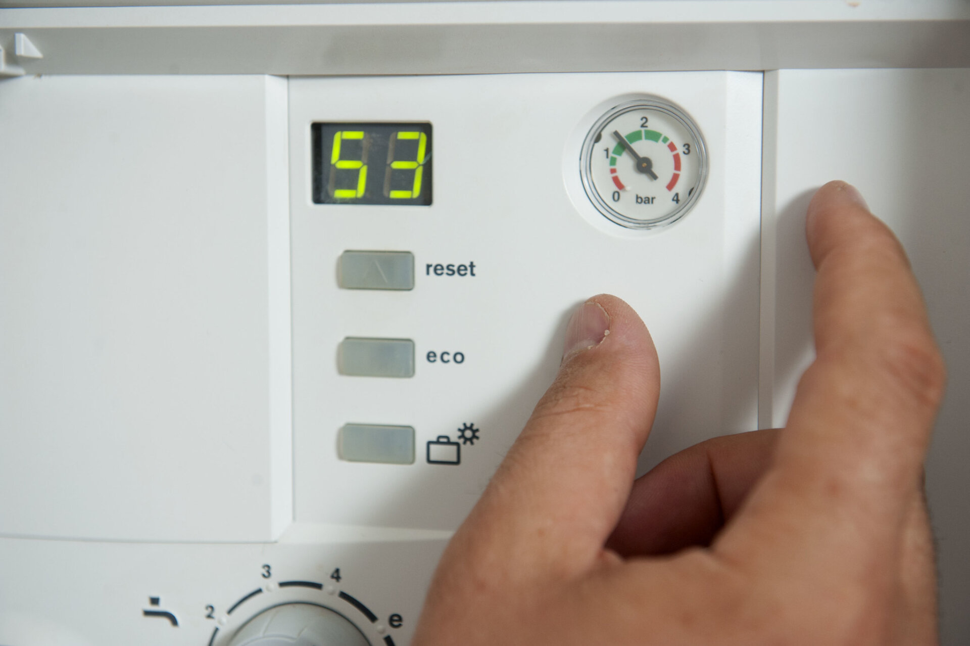 A boiler display panel with a hand near the reset button.