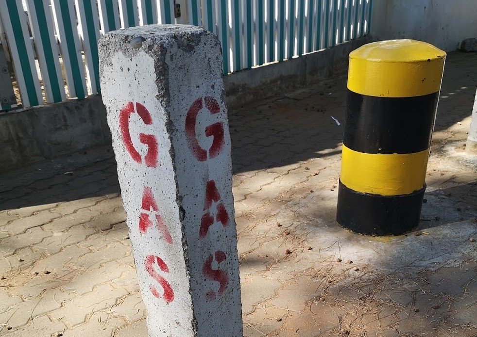 Two bollards on the street in Maputo, Mozambique. The closer one has GAS painted on it in red.