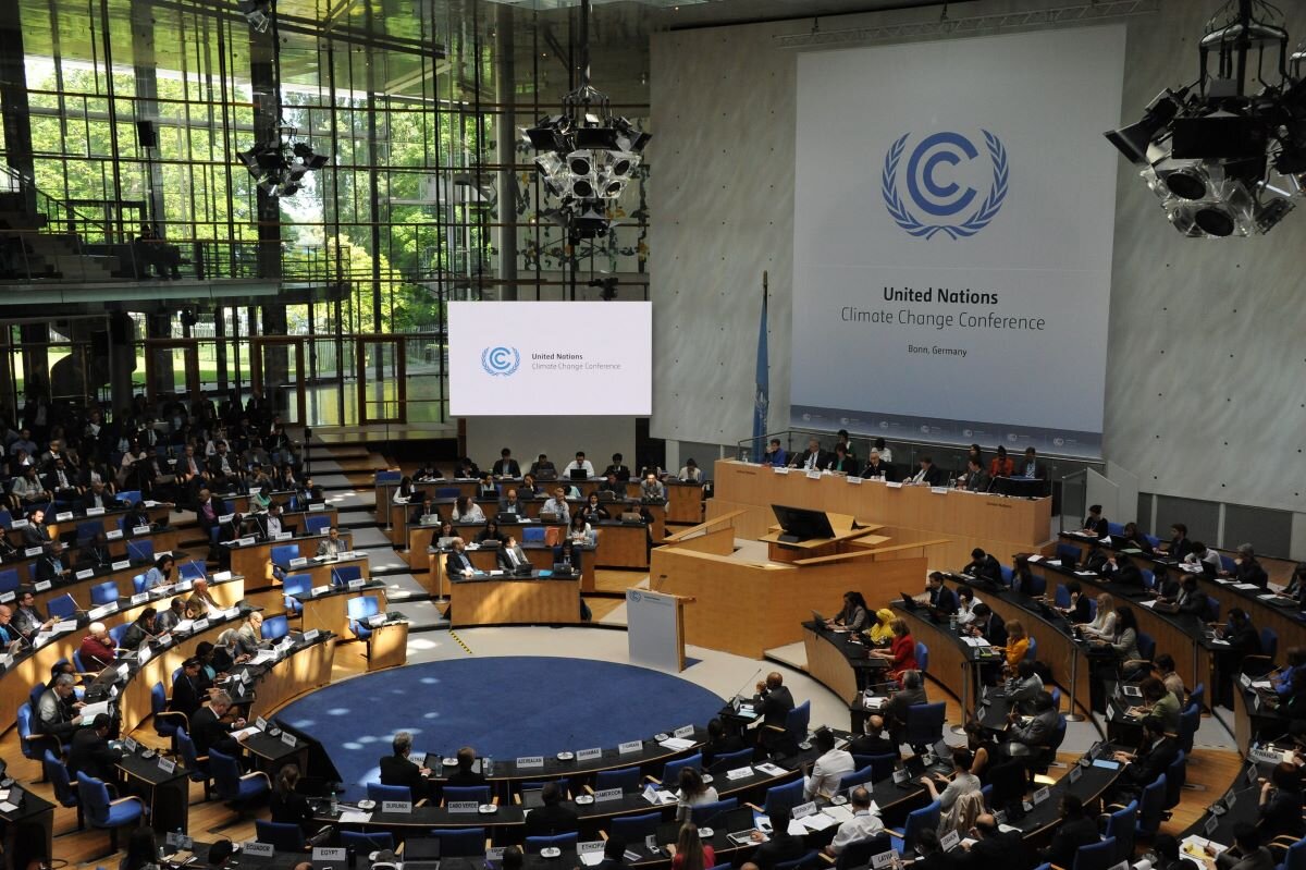 The inside of Bonn Climate Change Conference centre, showing the assembly and a large sign with the United Nations Climate Change Conference logo