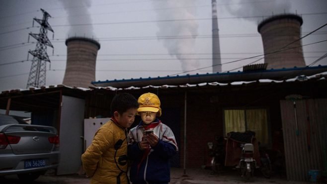 Boys in front of their house next to a coal-fired power plant on the outskirts of Beijing, China, ahead of the Paris climate summit in 2015. Photo by Kevin Frayer_Getty Images via Energy Monitor