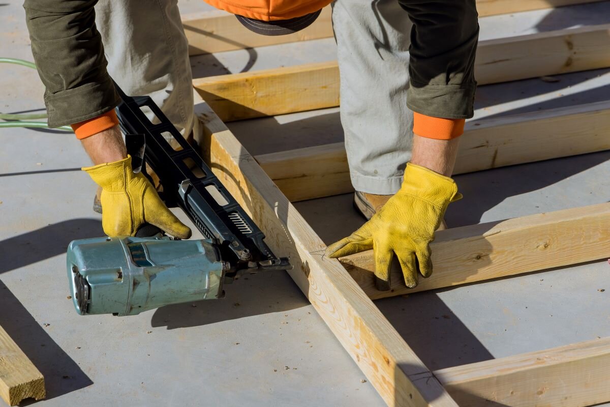 Builder nailing wooden beams works for construction in a home