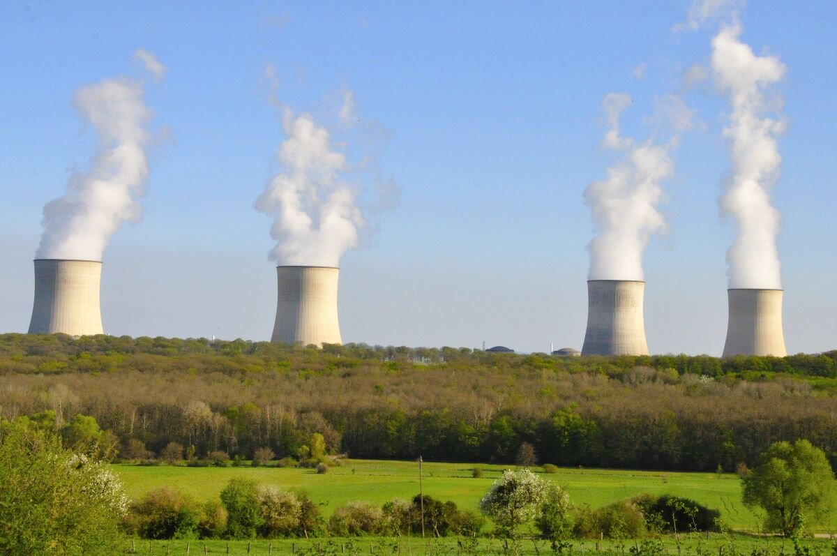 A green field with four factory chimneys behind, smoke coming out of each one. Cattenom nuclear plant, close to the Luxembourg border, a nuclear plant that would fall under the EU Taxonomy Delegated Act