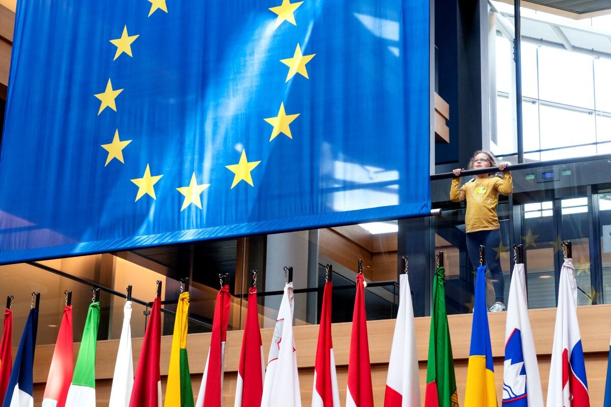 Child stands next to the European flag during the European Parliament's May plenary session, 2022. European Union