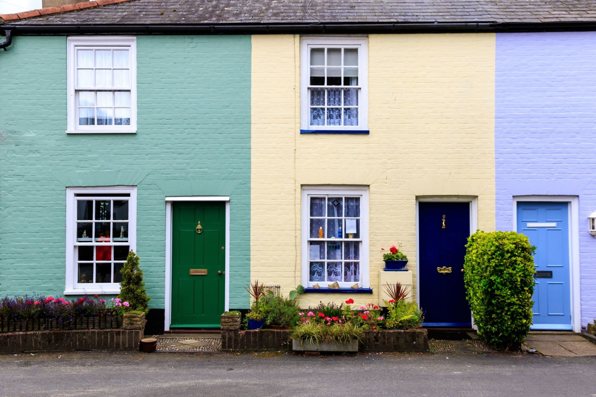 A row of terraced houses in Southwold, Suffolk, UK, painted green, cream, purple.