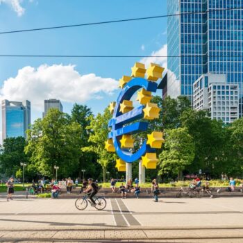 Cyclists and pedestrians gather around the euro sign in front of the European Central Bank headquarters in Frankfurt, Germany.