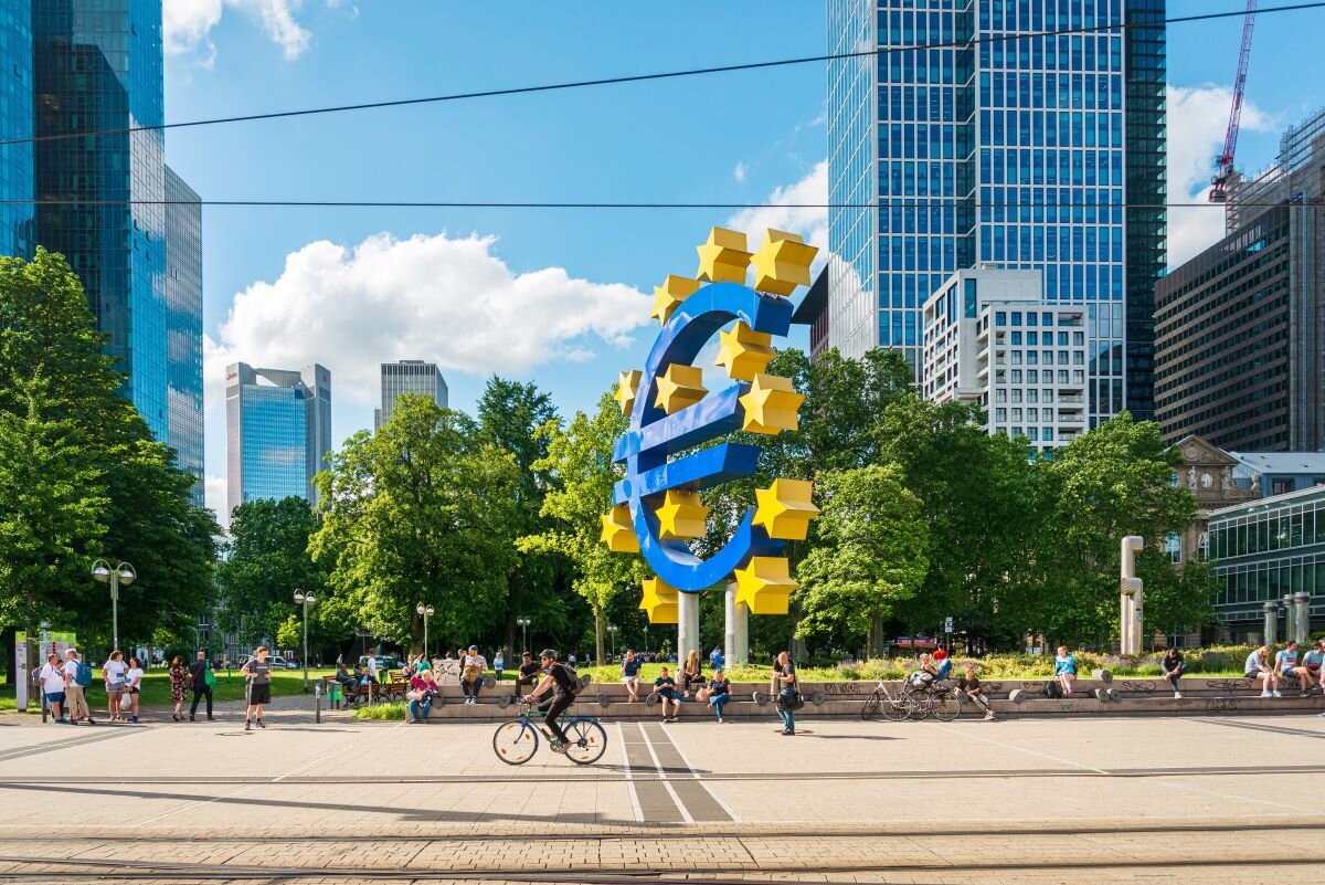 Cyclists and pedestrians gather around the euro sign in front of the European Central Bank headquarters in Frankfurt, Germany.