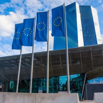 EU flags in Frankfurt, Germany, outside the new headquarters of the European Central Bank. Photo via Adobe Stock