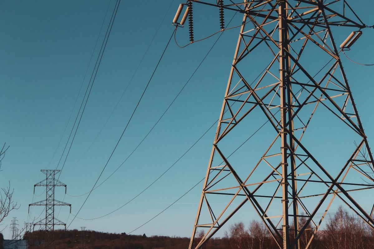 Electricity pylons against a blue sky. Photo by Sigmund on Unsplash.