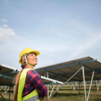 Engineer performing maintenance check of solar cells on solar farm.