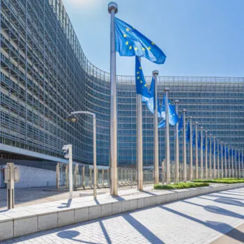 EU flags flying outside a large building.