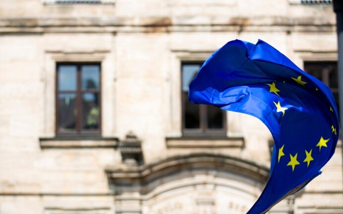 EU flag in front of an undetermined building.