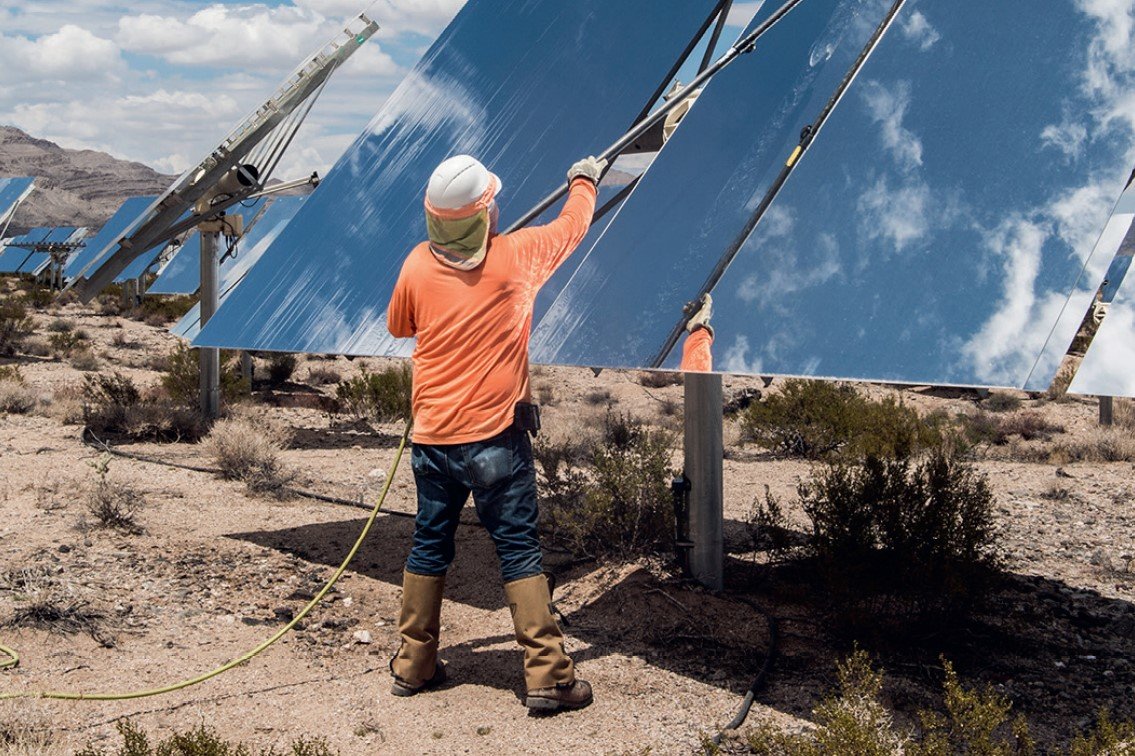 A worker cleans solar panels in the desert