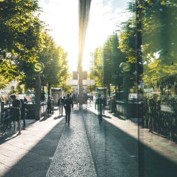 Green urban scene in Berlin with trees, glass building and cyclist. Photo by Tim David via Adobe Stock