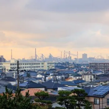 Houses against an industrial backdroup. Households paying a hydrogen levy on their bills will not see benefits, which are likely to be reaped mainly by fossil fuels companies. Photo via Adobe.