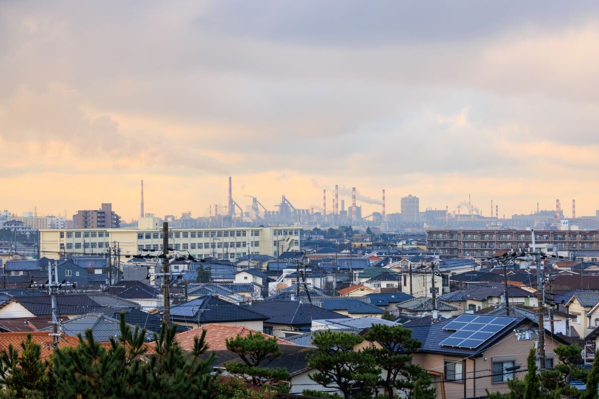 Houses against an industrial backdroup. Households paying a hydrogen levy on their bills will not see benefits, which are likely to be reaped mainly by fossil fuels companies. Photo via Adobe.