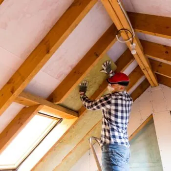 Man installing thermal roof insulation layer - using mineral wool panels. Attic renovation and insulation