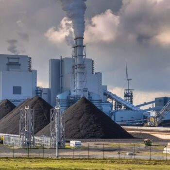 Heavy industrial coal powered electricity plant with pipes and smoke in black and white