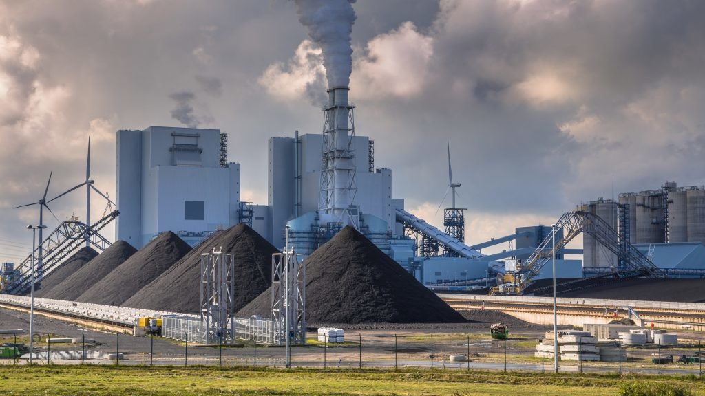 Heavy industrial coal powered electricity plant with pipes and smoke in black and white