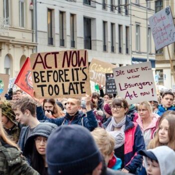 People asking for climate action in a demonstration with placards in English and German, where it can be read "Climate Action Now".