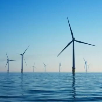 The image shows several windmills on a blue sea. It is Rampion's offshore wind farm, in the United Kingdom