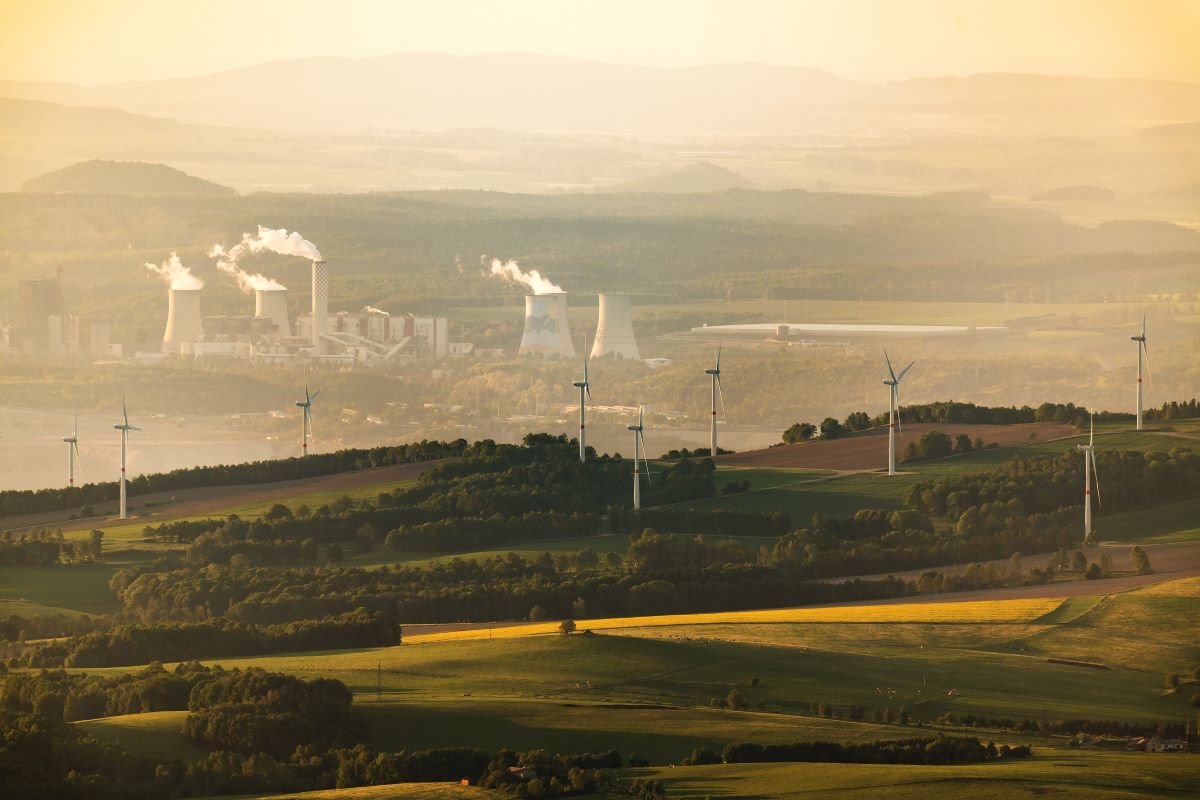 Rural landscape with coal factories in the background and wind turbines in front