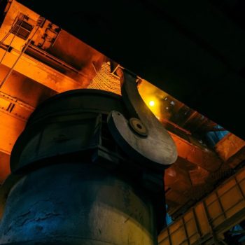 Angled shot looking up at a large hot furnace in a factory producing steel.