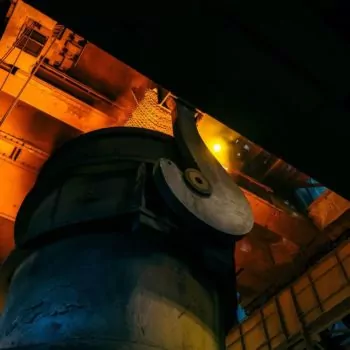 Angled shot looking up at a large hot furnace in a factory producing steel.