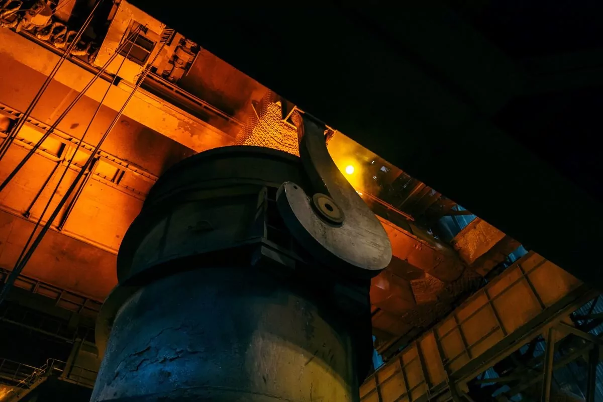 Angled shot looking up at a large hot furnace in a factory producing steel.